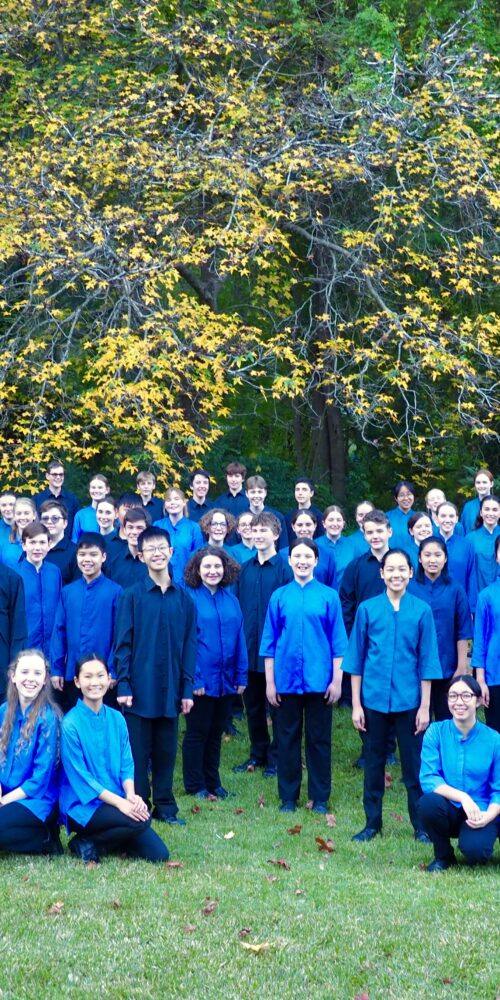 Choristers standing in a leafy setting